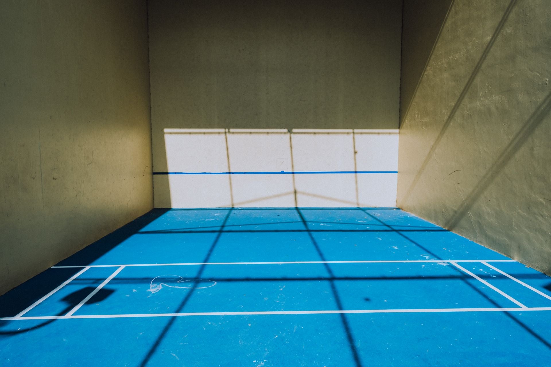 A pickleball court illuminated by sunlight inside an indoor facility