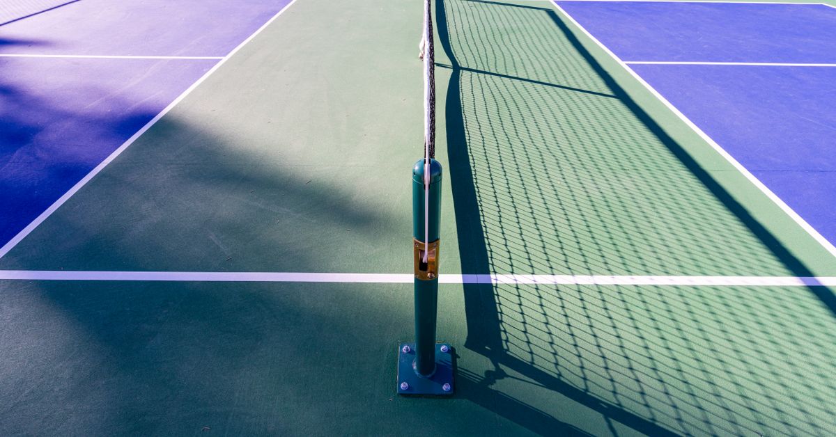 Empty pickleball court with net in summer sunlight