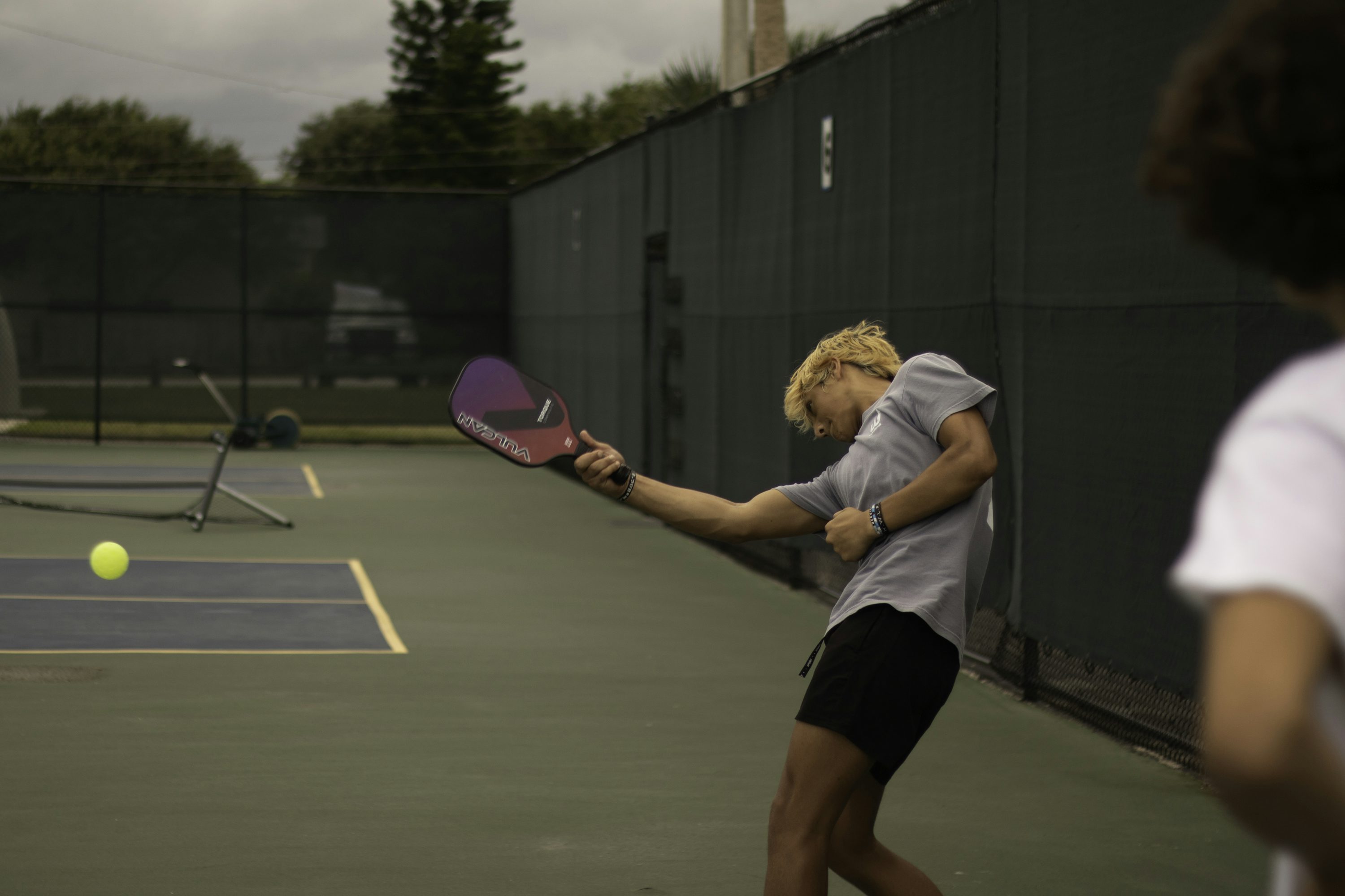 A woman hitting a pickleball with a paddle on court