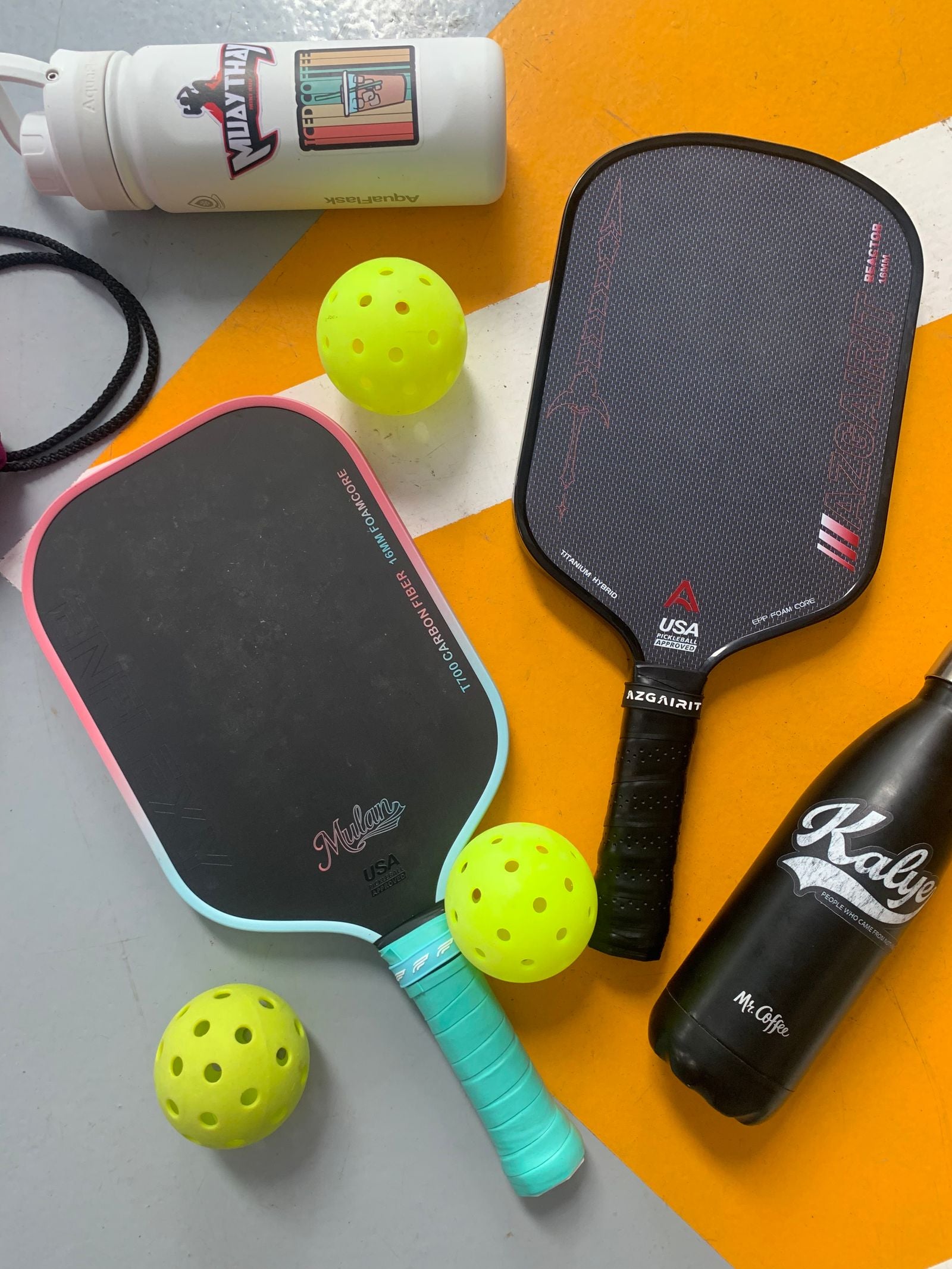Dark carbon fiber pickleball paddles laid out with pickleballs