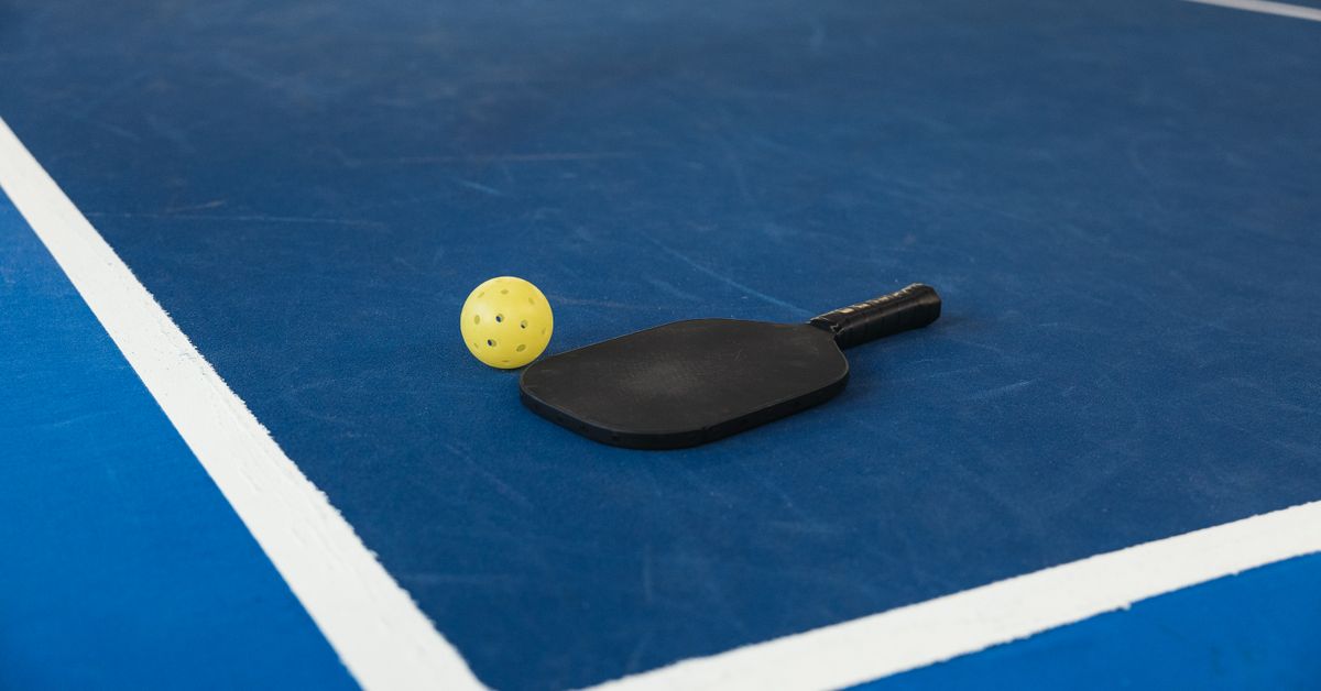Pickleball paddle and ball on a court