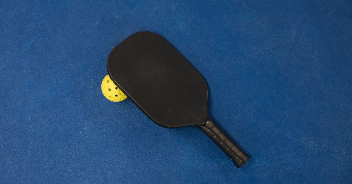 Pickleball paddle and ball on a blue background