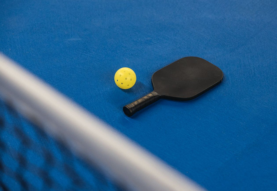Close-up of a pickleball paddle and ball on the court