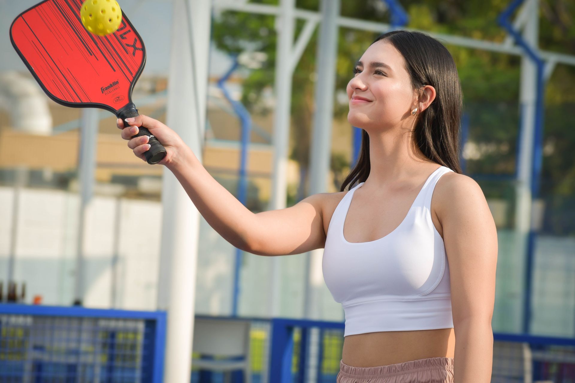 Young woman playing pickleball outdoors wearing colorful sportswear on a sunny day