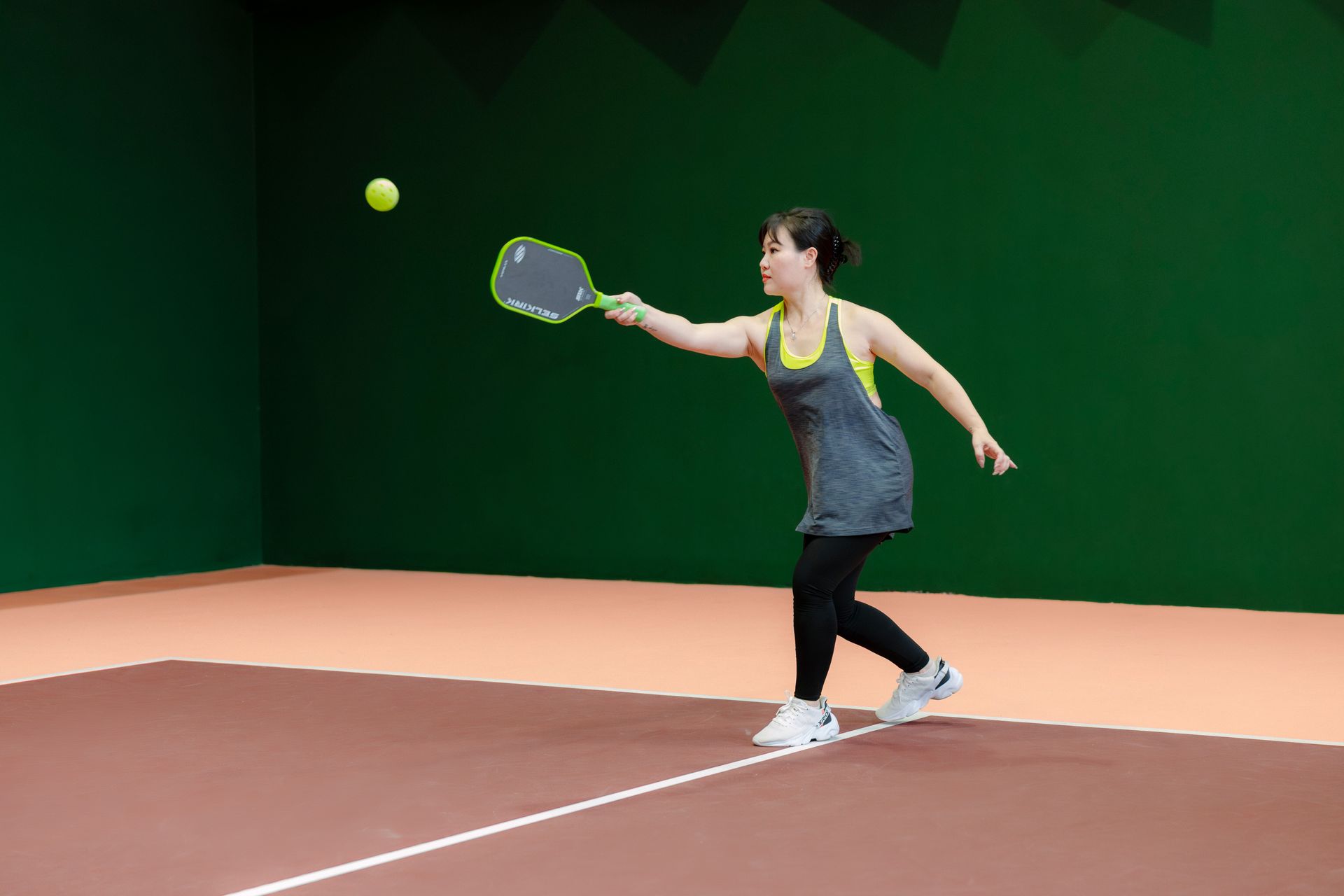 Woman playing pickleball on an indoor court