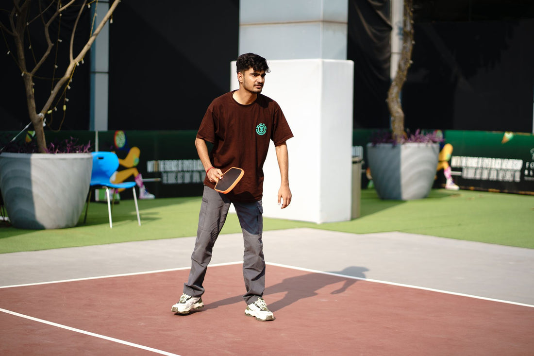 Young man actively engaged in a game of pickleball on an outdoor court