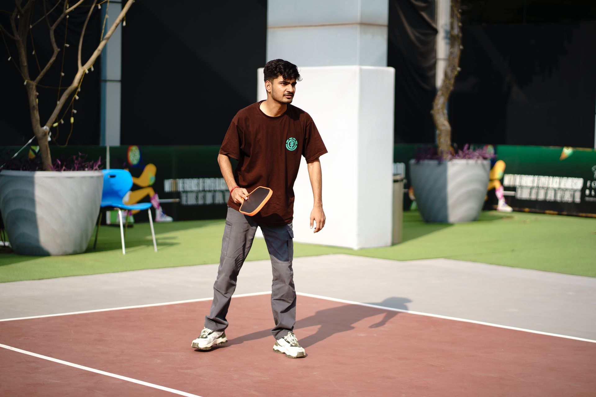 Young man actively engaged in a game of pickleball on an outdoor court