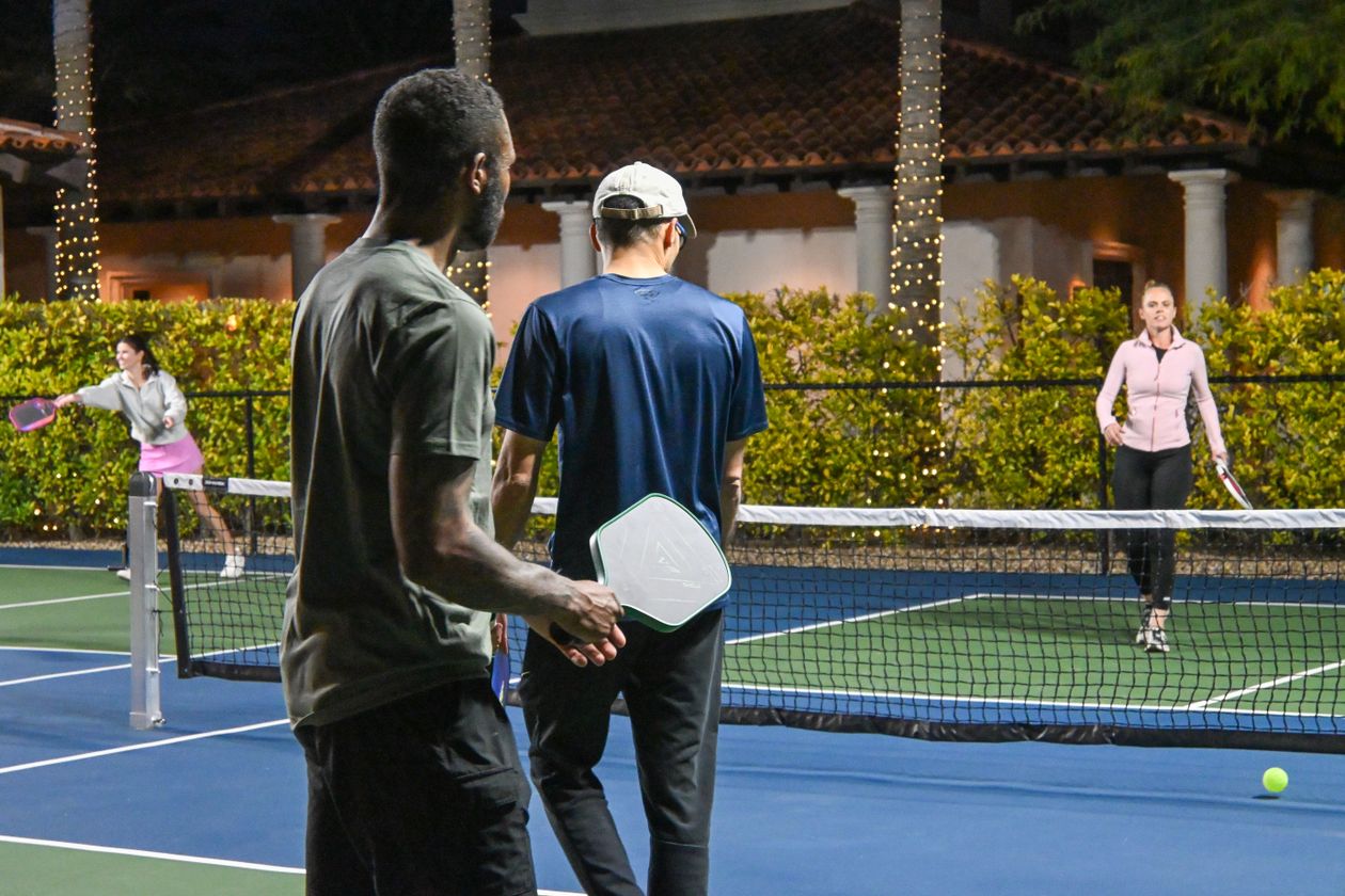 Energetic doubles pickleball match under the lights