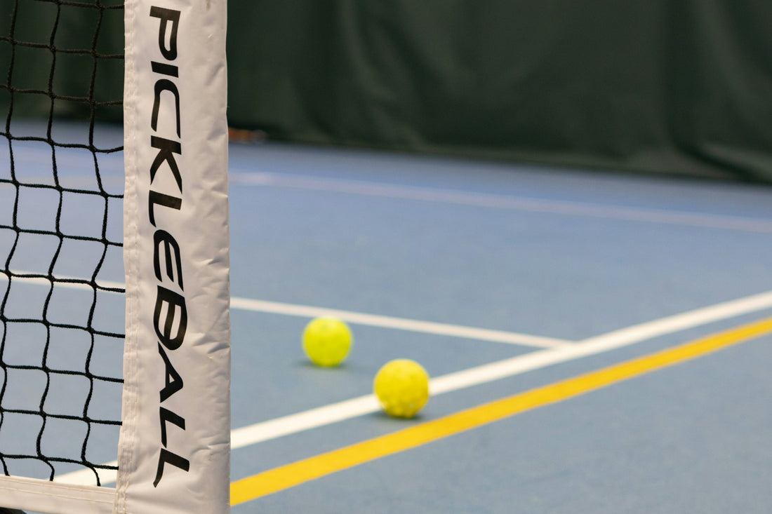 Three pickleball balls on a court near the net