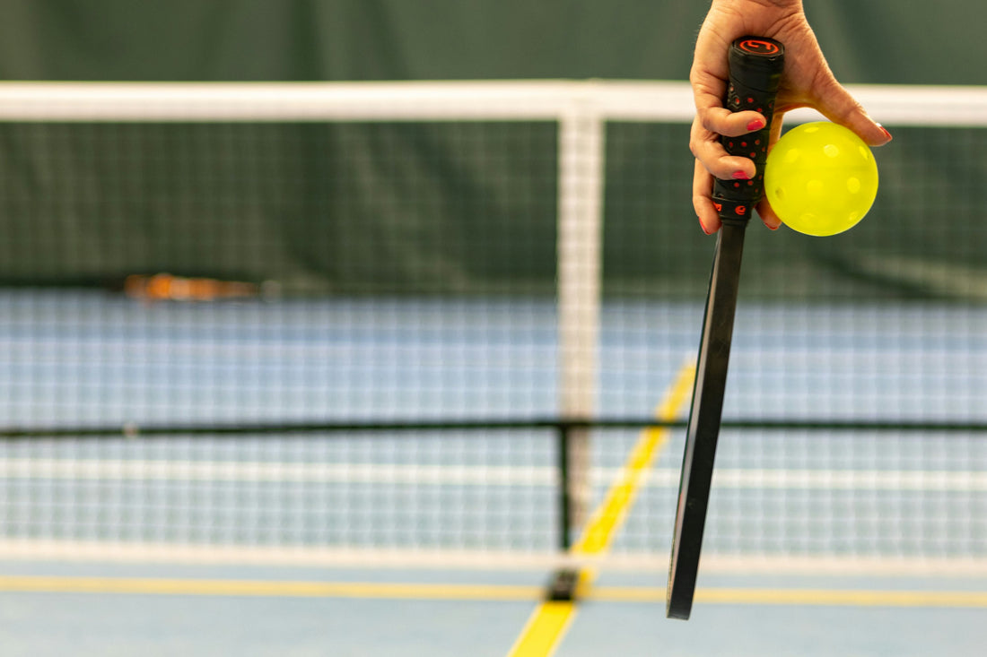 A player holding a pickleball and paddle
