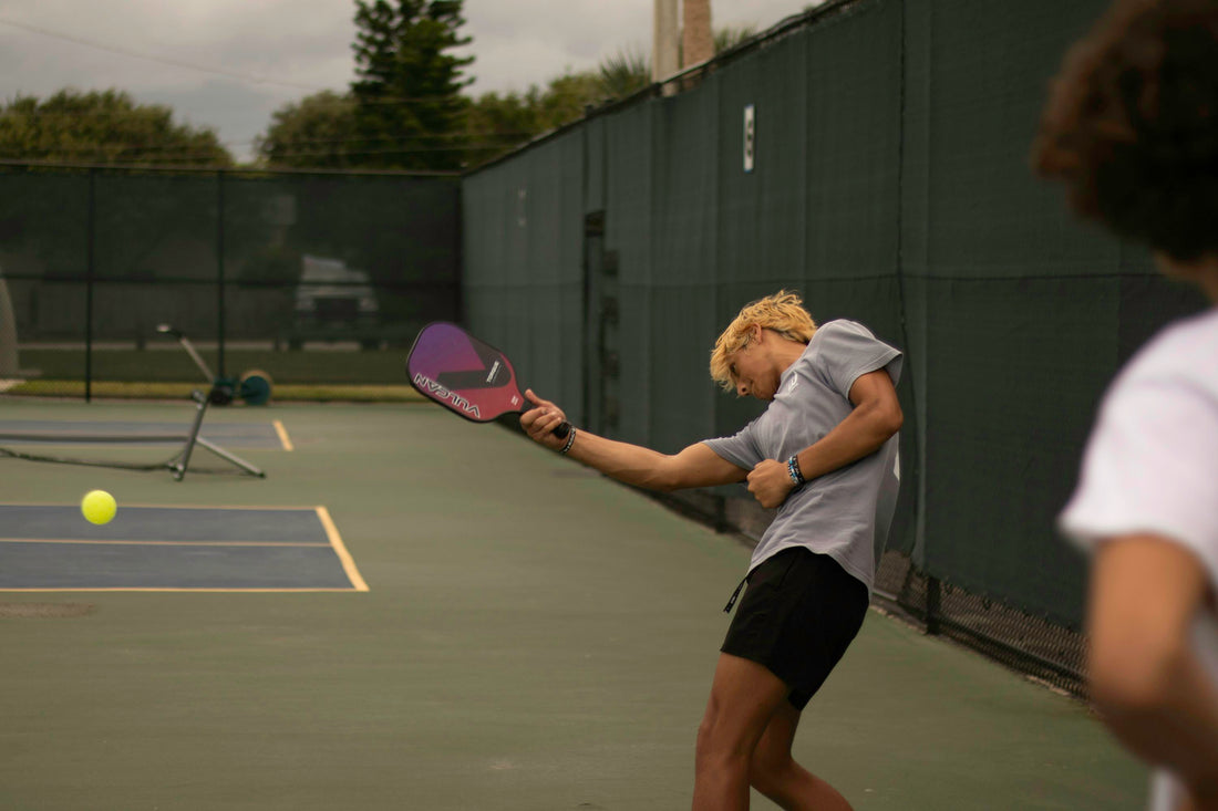A woman hitting a pickleball with a paddle on court