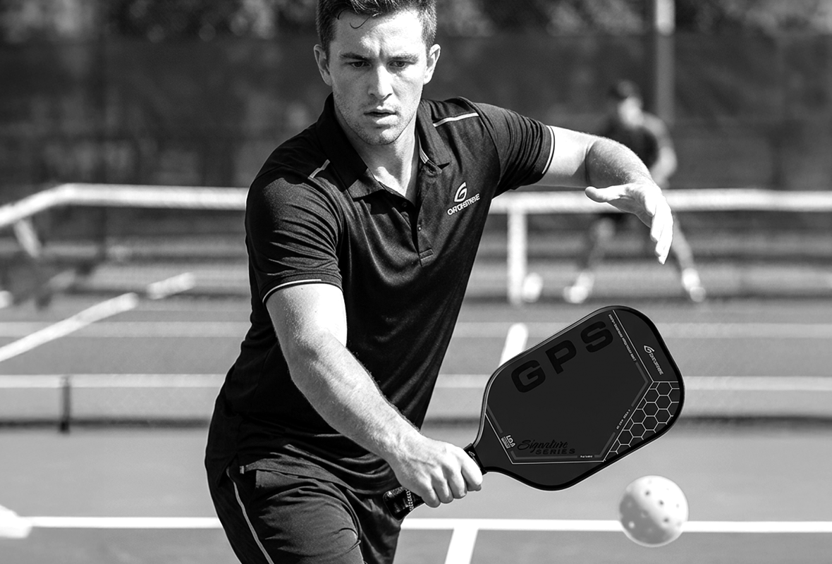 A black and gold GADOSTRIKE Gold Pro Series pickleball paddle is shown next to its matching box, featuring GPS branding, hexagon designs, and icons for durability, control, and USA manufacturing.