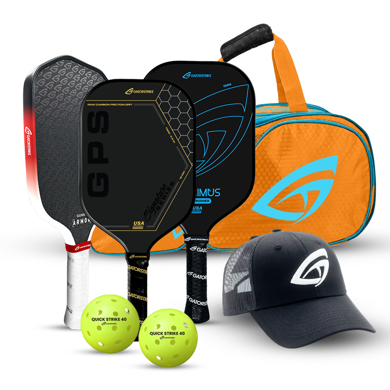 A set of pickleball gear including three paddles, two yellow perforated balls, an orange and blue duffel bag, and a black cap, all branded with the Gamma logo.