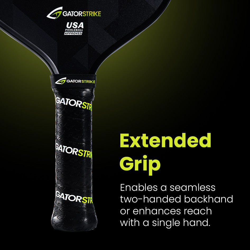 Close-up of a GatorStrike pickleball paddle handle wrapped in black grip tape with GATORSTRIKE text. The paddle is labeled USA Pickleball Approved. Text reads: “Extended Grip. Enables a seamless two-handed backhand or enhances reach with a single hand.”.