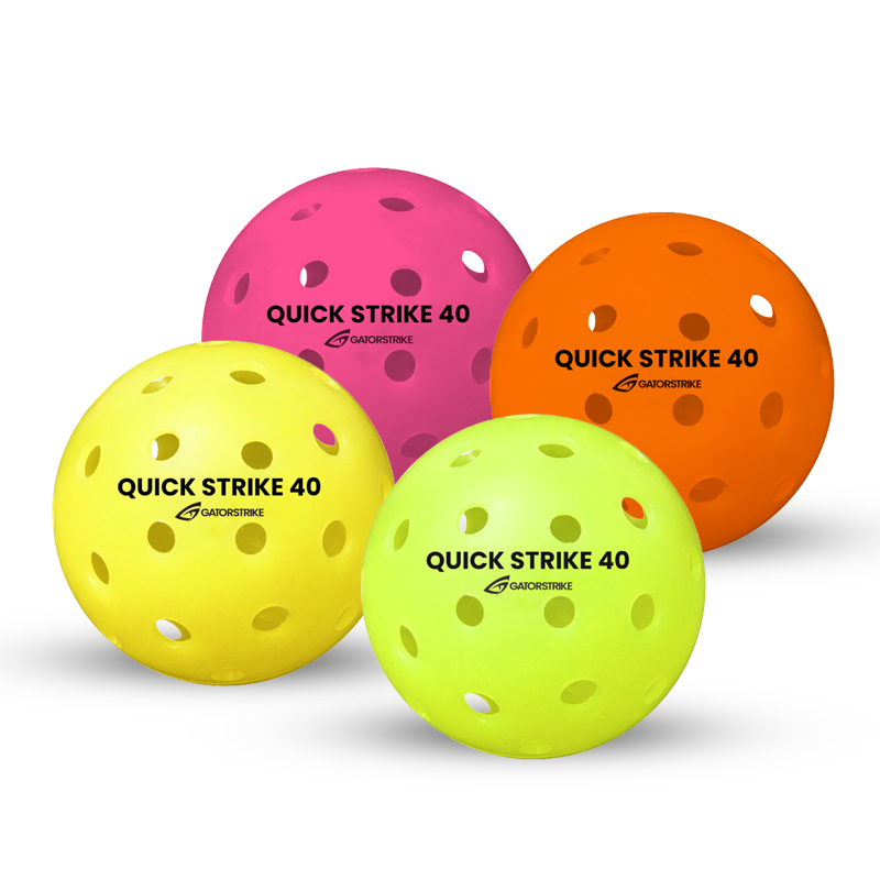 Four perforated plastic balls for pickleball are shown, each a different color: pink, orange, yellow, and light green. They are labeled “QUICK STRIKE 40” with a logo. The balls have evenly spaced holes across their surfaces.