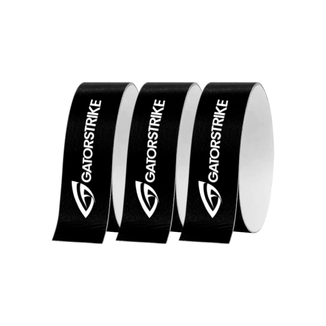 Three upright black rolls of GATORSTRIKE paddle edge protective tape are displayed in a row, each featuring the white GATORSTRIKE logo and name printed vertically. The plain, light gray background highlights the brand’s design.