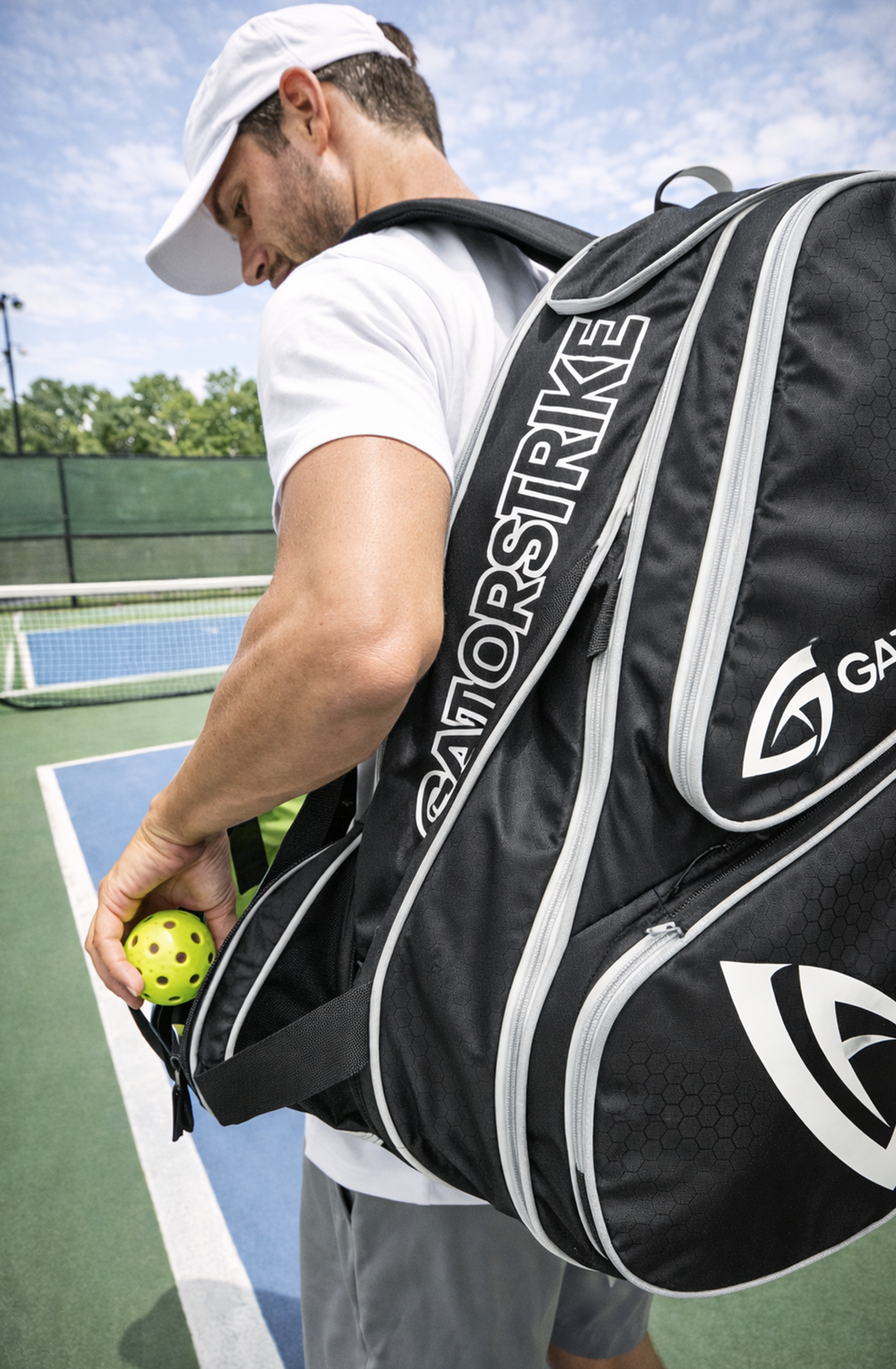 A man in sportswear carries a large GatorStrike bag and a yellow pickleball, referencing the GatorStrike pickleball manual.